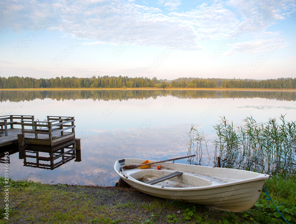 Obraz premium Small pier on a lake shore. Finnish relaxation moment during the holidays. Sunny and calm weather. Place for swimming and fishing.