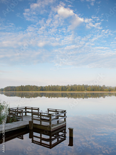 Small pier on a lake shore. Finnish relaxation moment during the holidays. Sunny and calm weather. Place for swimming and fishing.