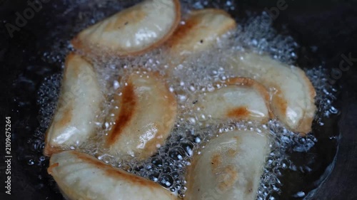 Dumplings frying in hot oil in a pan, with bubbles and a crispy golden surface