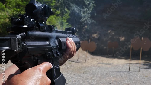 Woman Shooting with an Assault Rifle with Smoke in an Outdoor Shooting Range in a Sunny Summer Day in Switzerland.