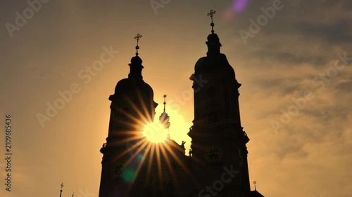 Abbey of Saint Gall with Clock Tower and Sunbeam in Backlit Against Orange Sky in Sunset in City of St Gallen, St Gallen Canton, Switzerland.