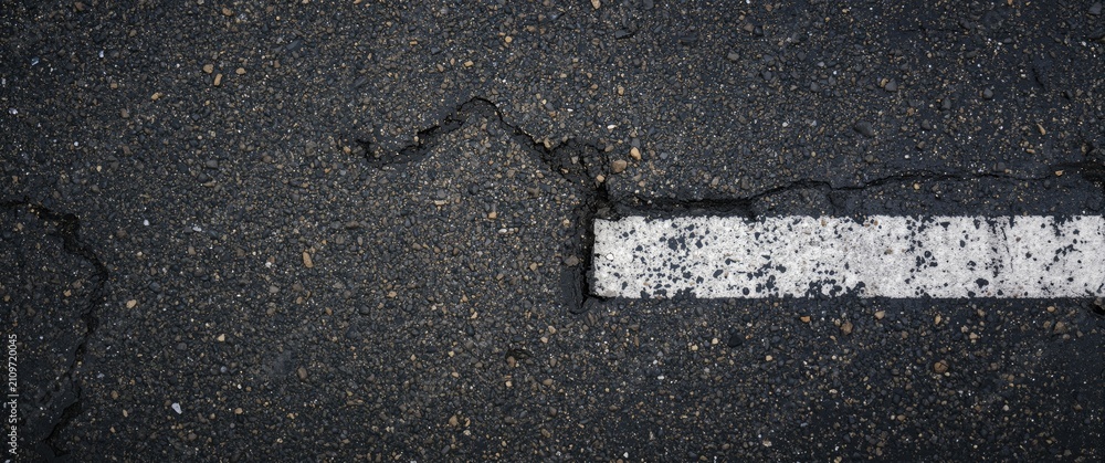 Fototapeta premium Cracked Asphalt Road Surface with Distressed White Line