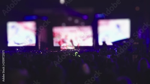Concert audience facing brightly illuminated stage at night