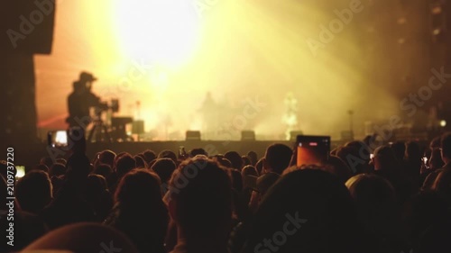 Festival audience facing brightly lit concert stage at night