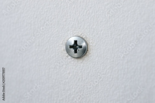 A single screw mounted on a wall, used for hanging objects or decorative purposes