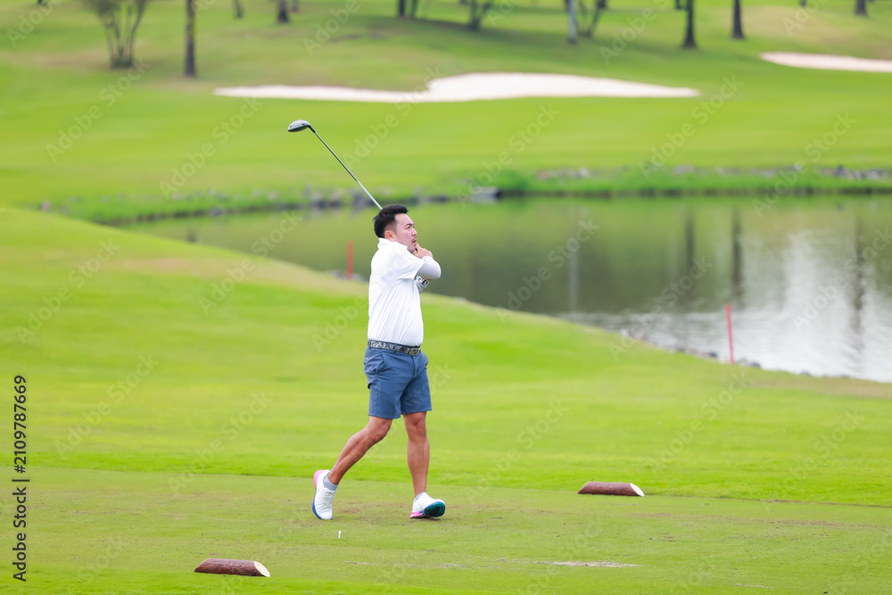 Obraz premium professional golfer on field. Asian Man Golfer Hitting Golf Shot on golf Course. teeing off golf ball. Sport outdoor