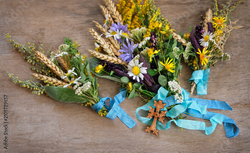 Принти на полотні Herbs tied to sacred bouquets with ribbons and wooden cross on rustic table close up