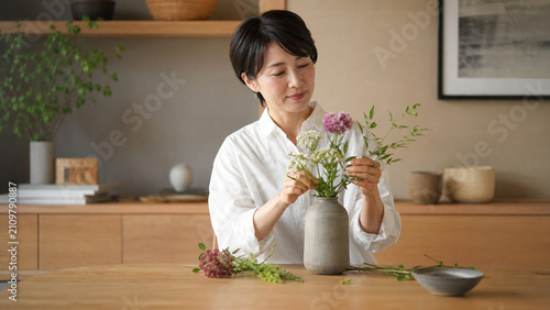 自宅で季節の花を花瓶に生ける日本人女性