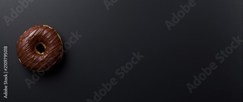 Tableau sur toile Chocolate Glazed Donut on Dark Surface with Negative Space