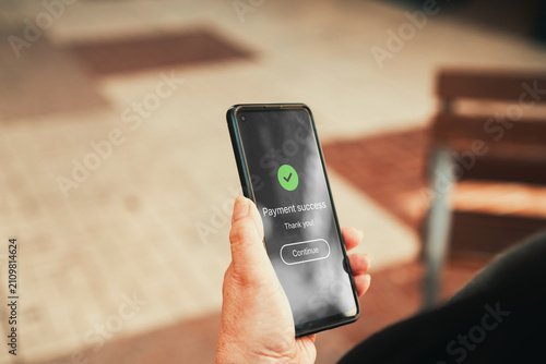 Payment Success Confirmation Screen on Smartphone Outdoors. Online shopping, mobile banking, e-commerce transactions, and digital payment security concept.