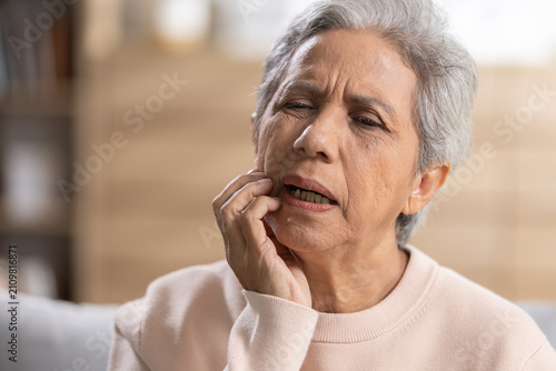 Obraz na płótnie Senior woman suffering from toothache while touching painful cheek at home