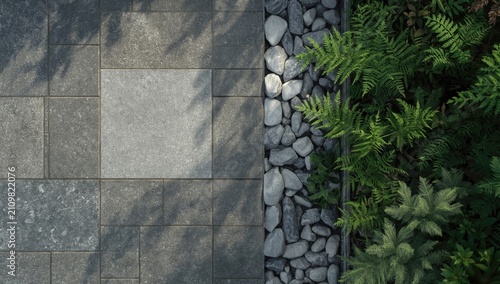 High angle view of textured stone paving in grey shades bordered by smooth pebbles and lush greenery in stylish garden setting