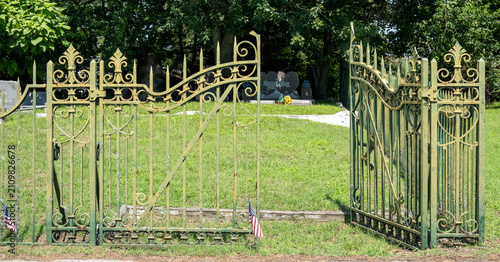 Photography An ornate pair of open weathered wrought-iron cemetery gates