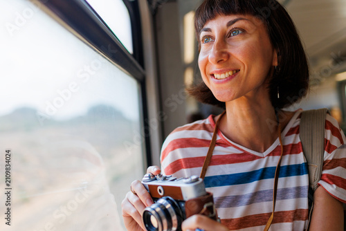 train travel. Young woman enjoying a train ride with a camera. tourist takes pictures of beautiful tourist places on camera. film camera.