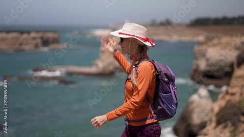 A mature woman enjoys hiking the coastal trail near the lighthouse in Mendocino California, smiling as she walks by the ocean.