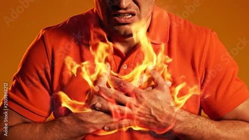 Man clutching his chest with dramatic fire effect, symbolizing heartburn, chest pain, acid reflux, heart attack risk, emergency healthcare, medical concept, and health awareness.