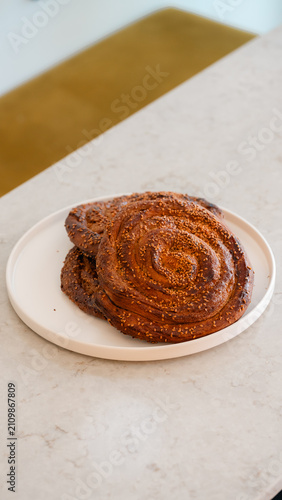 фотографія Sweet Cinnamon Swirl: Two golden brown, freshly baked cinnamon swirl pastries rest on a minimalist white plate, hinting at a delightful morning treat or a satisfying afternoon snack