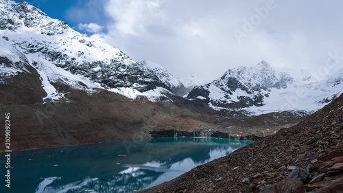 4K Timelapse of Ghepan Lake, snow covered mountains and clouds moving in sky at Lahaul, Himachal Pradesh, India. Natural landscape of India. Travel concept.  High altitude glacial lake in Himalayas.