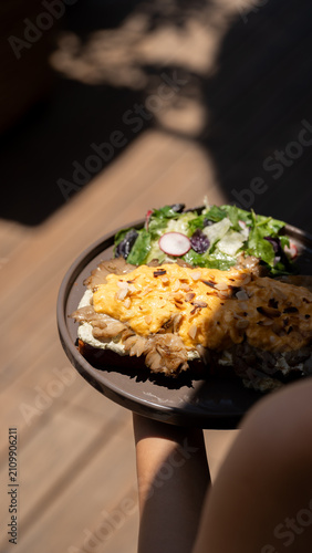 Obraz na płótnie Delicious Brunch Feast: A delectable brunch dish featuring savory shredded meat topped with melted cheese, served alongside a fresh, vibrant salad with radish and greens