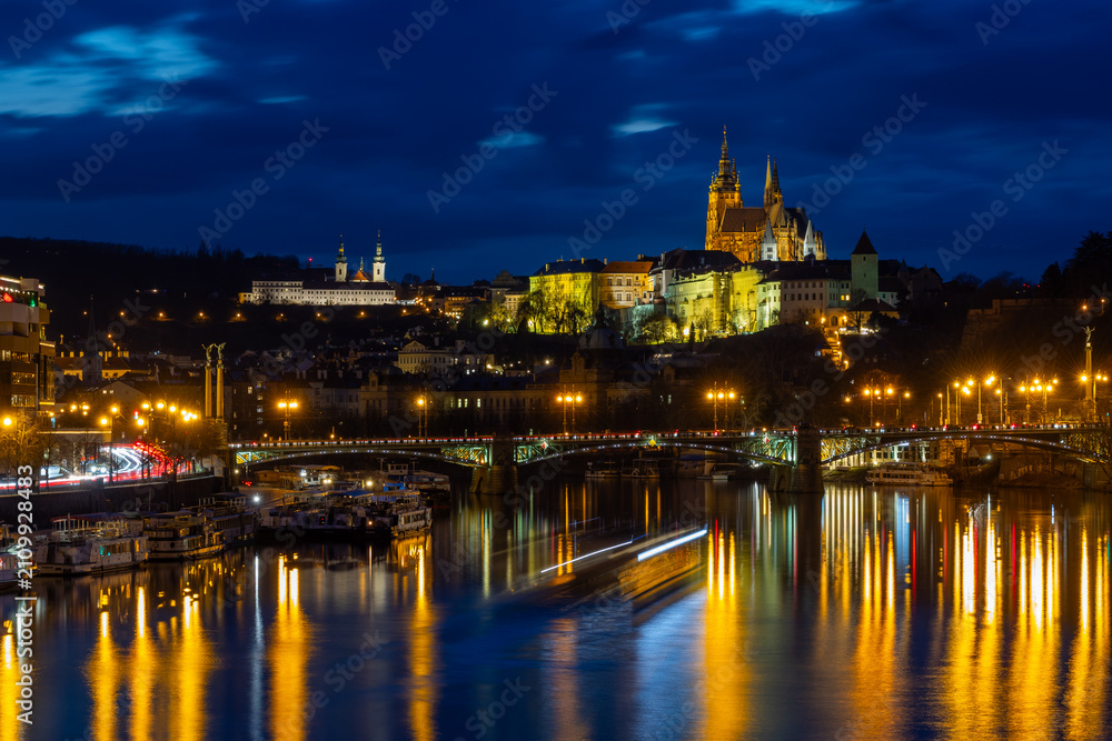 Obraz premium Illuminated Prague Castle, Strahov Monastery and Vltava River weir at blue hour twilight, Czech Republic