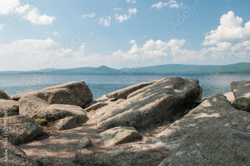 Summer view of Turgoyak lake with huge boulders on its shore in the foreground, South Ural, Russian Federation