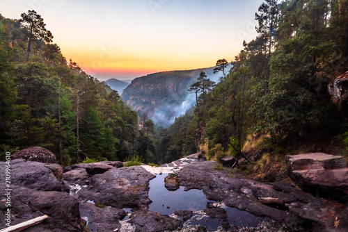 River between mountains with mist at sunset in a beautiful valley and forest in the Sierra Madre Occidental in Mexiquillo, Durango