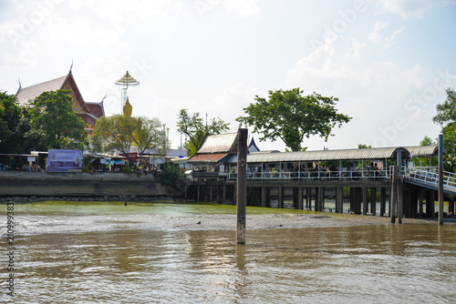 BANGKOK, THAILAND – JUNE 18, 2026: Riverside temple and observation tower along the Chao Phraya River seen from a ferry crossing in Bangkok.
