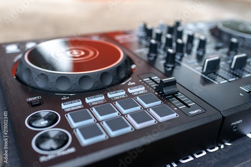 Fotografie professional DJ controller with illuminated jog wheel, performance pads, mixer faders, audio controls