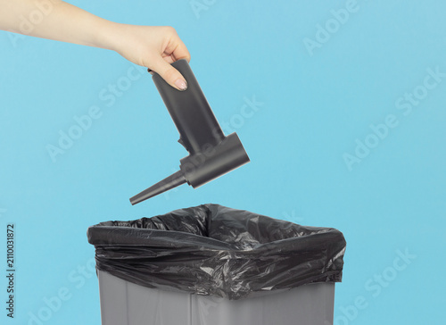 Throwing a portable electric air duster with nozzle attachment into the trash can, holding a electric air duster in front of the trash can