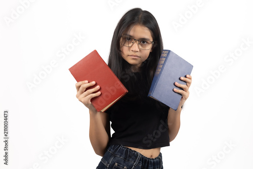 Tired young student girl holding stack of study textbooks before exam