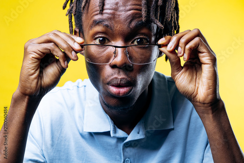 Konstfotografi Young black man looking with a wide-eyed, surprised expression, pushing up his g