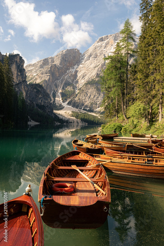 Foto Traditional rowing wooden boats on calm water of Lago di Braies lake in mountain landscape of Dolomites Alps Italy