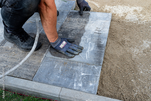 Принти на полотні Worker laying paving slabs on a sand bed for a new patio