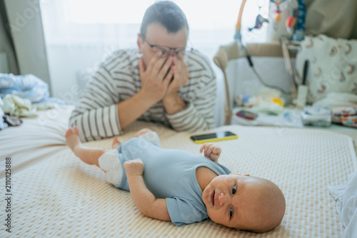 Obraz na płótnie Young father feeling overwhelmed and anxious, covering his face with hands while