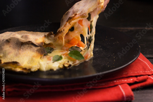 Fotografía Baked Italian margherita calzone stuffed with mozzarella, tomato and basil