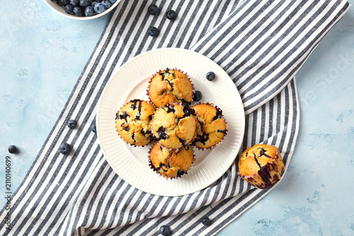 Top view of blueberry muffins on plate with striped towel