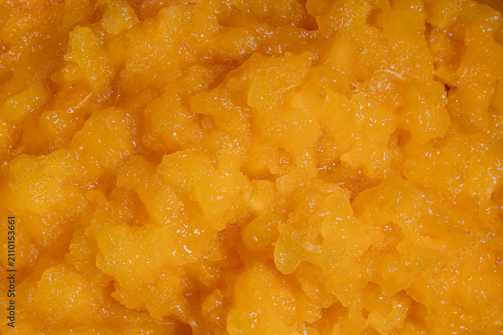 Obraz premium Bright orange mango puree texture closeup with glossy fruit surface