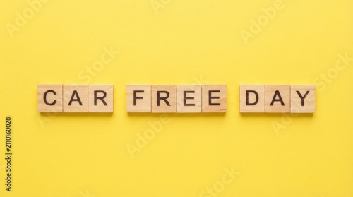 Wooden blocks spelling out the words car free day placed on a bright yellow background to promote environmental awareness for world car free day event