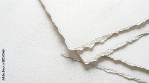 Abstract background featuring layers of white torn paper with rough edges and soft shadows on a white surface