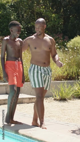 Vertical video: Walking dad and son from pool steps by pool, chatting in swim trunks while bonding