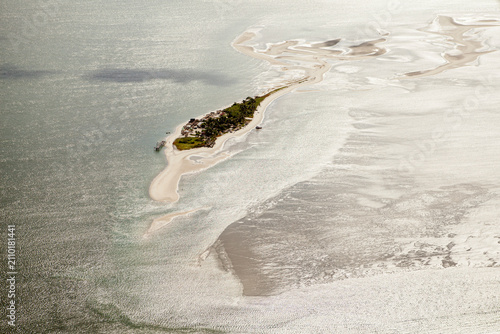 Vista aérea da Coroa do Avião, banco de areia e ilha no litoral de Pernambuco, cercada por águas rasas e marés, destacando a beleza natural do estuário e da costa nordestina.