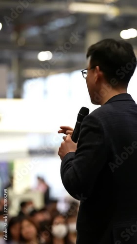 Man in business suit speaking to audience, corporate presentation.