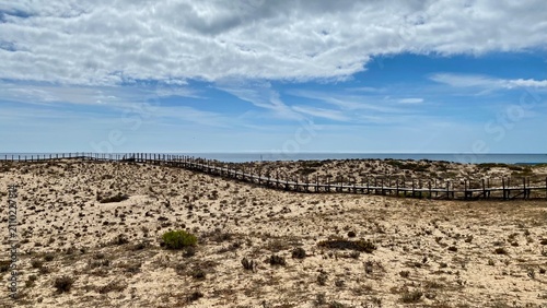 Wooden boardwalk across sand dunes in Ria Formosa Natural Park, Algarve, Portugal