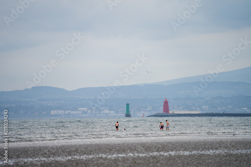 Konstfotografi People wade in sea near lighthouses in Dublin bay