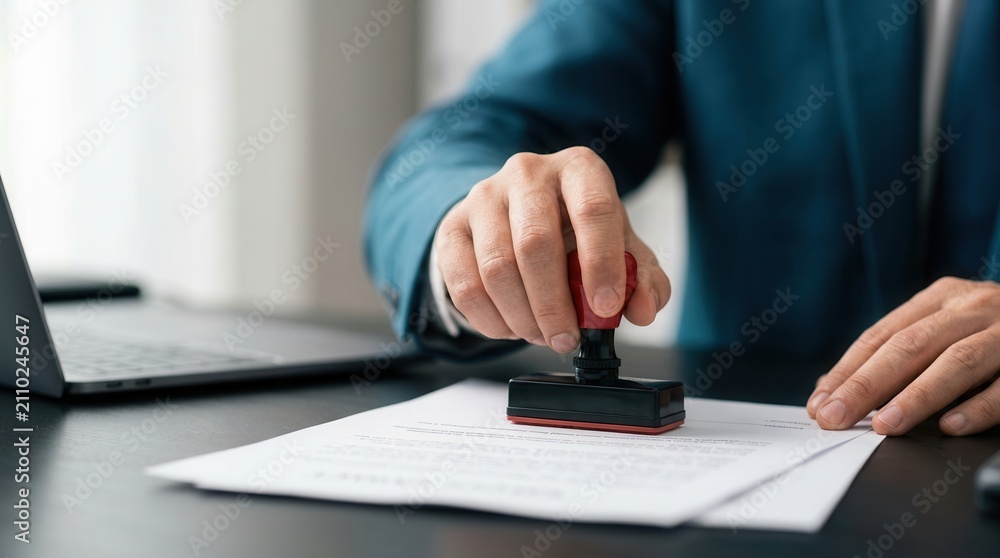 Fototapeta premium Businessman using an approval stamp to validate and manage business documents and agreements.