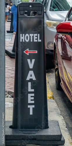 Vertical Image of Hotel Valet Sign on the Sidewalk Next to Parked Cars in Downtown New Orleans, LA, USA