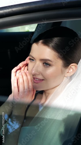 Beautiful elegant bride sitting in a car and smiling gently close up.