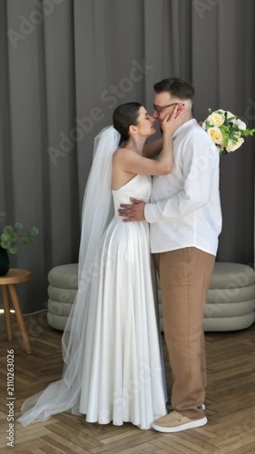 Romantic newlywed couple embracing and sharing tender moment in modern studio.