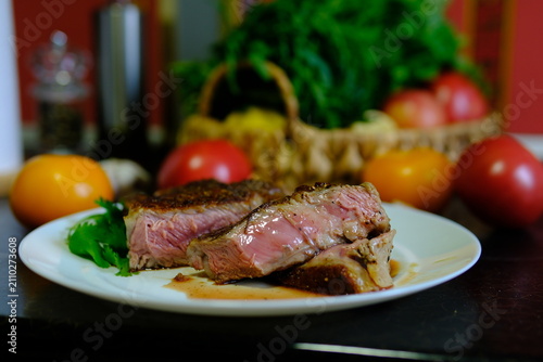 Tender beef reveals a warm pink center after slicing, showing a perfect medium rare texture. Fresh vegetables and colorful tomatoes complete an elegant restaurant serving.