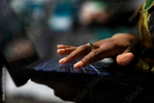 Slika na platnu Close-up of an army soldier typing on a laptop and using tracking software to monitor hostile threats from a military operations base during surveillance